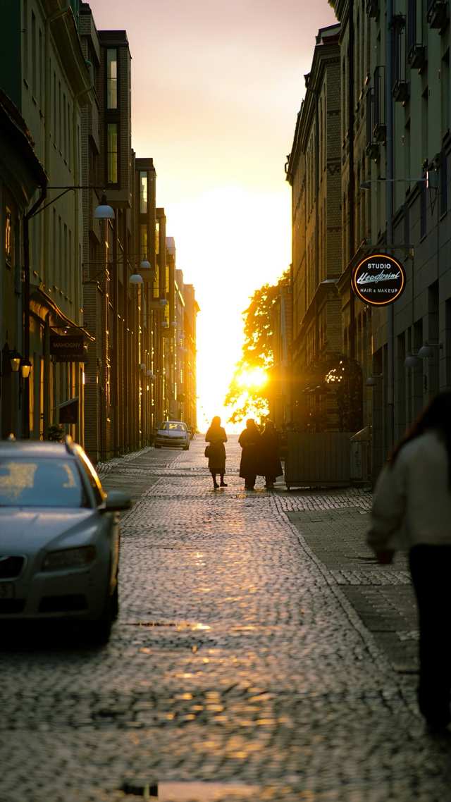 Bil parkerad på en kullerstensgata i solnedgången