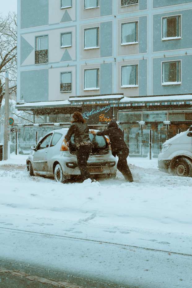 Två personer skjuter på en bil som fastnat i snön